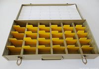 Open metal slide case showing interior compartments, dividers, index card, handle and latches
