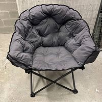 Front view of grey padded saucer folding chair on black metal frame