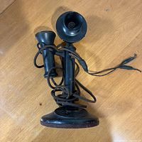 Full view of candlestick telephone lying on side showing base, stem, mouthpiece, receiver and cord
