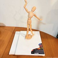 Mannequin standing on base beside two canvases