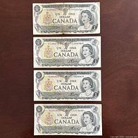 Four 1973 $1 banknotes laid out flat