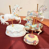 Three carousel horse figurines, two on music box bases, one on cloud base