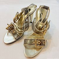 Pair of metallic strappy Dolce & Gabbana heels angled view