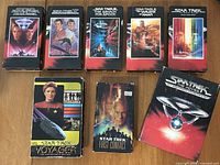 Front view of all seven VHS tapes showing cover art
