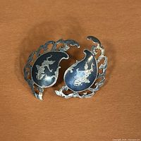 Front view showing niello enamel, Thai dancer figures and paisley shape, both earrings