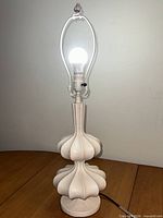 Full view of white tiered lamp on table
