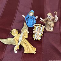 Front view of all four figurines on red cloth