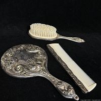 Mirror, brush and comb arranged on black background showing overall design