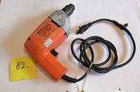 Left side view of Black & Decker orange corded drill with cord coiled
