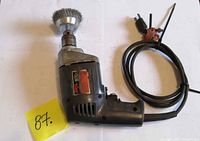 Full view of Skil 3/8-in corded drill with wire brush attached and cord coiled