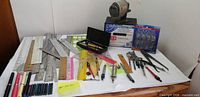 Overall view of lot on table showing rulers, pens, tools, sharpener, labels