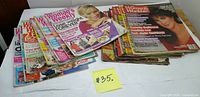 Two stacks of magazines showing Woman's Weekly and Woman's World covers