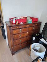 Front view showing four drawers, metal pulls, inlay details, items on top not included