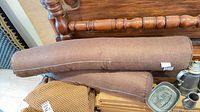 Both brown cylindrical bolster pillows stacked