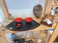 Shelf with bento set, mask, flask bottle, sundial base visible, lower glassware