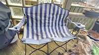 Full view of folded-out two-person striped camp chair on deck