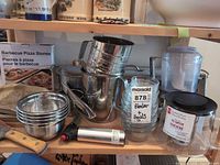 Shelf with fish poacher, flour sifter, mixing bowls, processor bowl, teapot, torch, pizza stones box
