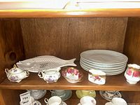 Shelf showing fish platter, stack of plates, cream and sugar set, Royal Albert pieces