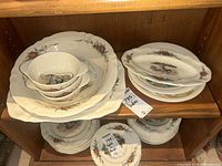 Overview of shelf showing platter, serving bowl, handled bowls and stack of plates