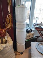 Full view of stacked cylindrical paper floor lamp beside window