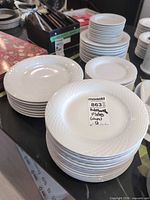 Stacked chargers, plates and bowls showing lattice rim pattern and MaxSold sticker