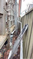 Both ladders stored outdoors between fence and structure