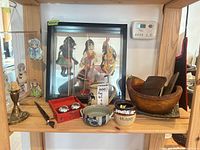 Overall shelf view showing framed puppets, candlestick, mug, bowls, honey crock, wooden bowl, lacquer box