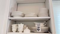 Two shelves showing stacked dinnerware, gravy boat