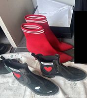 Red Nordstrom boots beside open shoe box and black Love Moschino rain boots