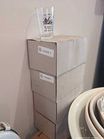 Stack of four plain cartons with one sample glass on top