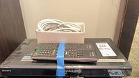 Top view of Sony BDP-S350 player with two remotes and boxed cable