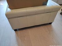 front view of cream faux leather storage bench showing peeling finish