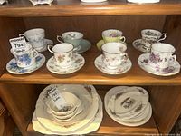 Eight teacup and saucer sets displayed on shelf