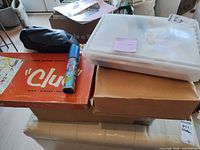 Overview showing Clue game box, kaleidoscope, plastic bin, cardboard boxes