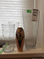 Four vases grouped on windowsill: three clear glass and one ceramic with yellow flowers