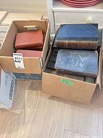 Two cardboard boxes filled with large hardcover books