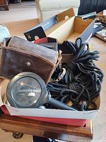 Mixed lot in box showing magnifier, rope, leather case