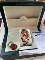 Open Rolex box showing Datejust watch, hang tags, maxsold card