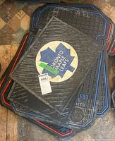 Stack of rubber mats showing Toronto Maple Leafs and others beneath