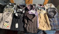 Overview of 20 folded shirts showing variety of colours, patterns, some tagged