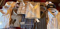 Assorted new men’s shirts laid out showing packaging and tags