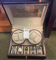 Open display case showing five wristwatches and two watch holders