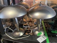 Five brushed metal mushroom table lamps grouped on shelf