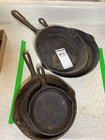 Four stacked cast iron frying pans showing sizes and condition