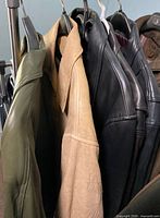 Five leather jackets hanging on rack showing colors and styles