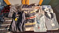 Group shot of all twelve packaged shirts and sweaters laid out on table