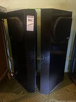 Front and side view of both black floor speakers with grilles and Optimus logo visible