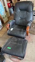 Front view of black reclining glider rocker and ottoman showing upholstery and wooden arms
