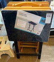 Front view showing sealed black laminated table attached to stand with four wood tables behind
