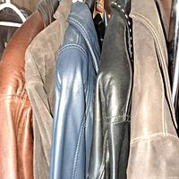 Group of hanging leather and suede jackets in various brown, black, and tan shades
